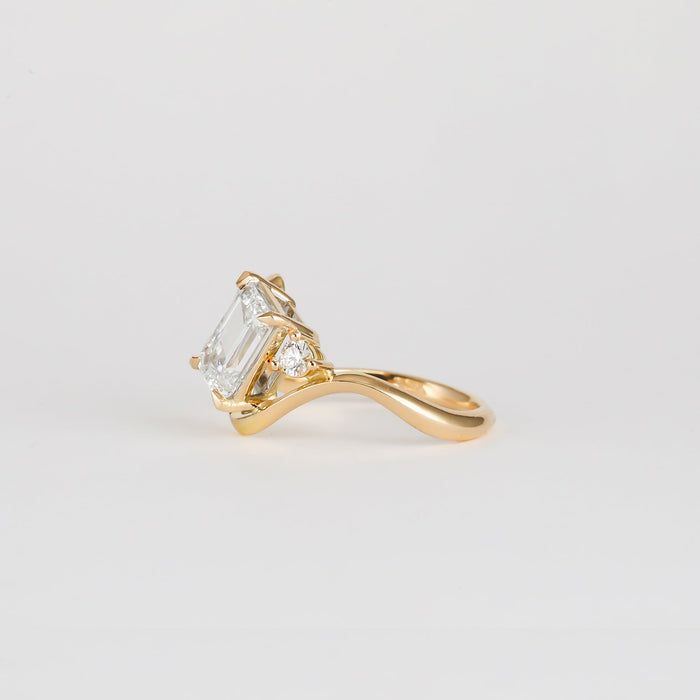 Emerald cut moissanite swirl shank engagement ring with a round accent in yellow gold, view 2