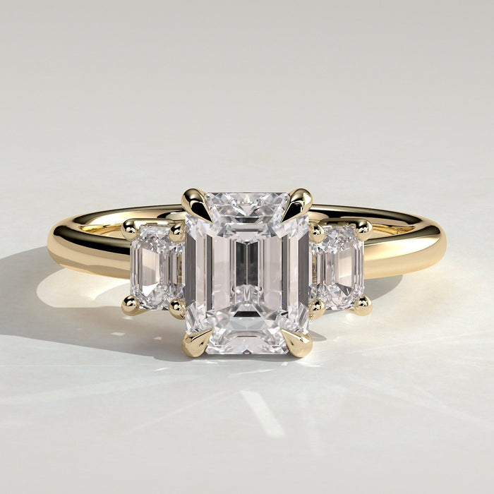 Emerald cut moissanite three stone engagement ring with step cut side stones in yellow gold