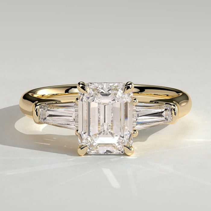 Emerald cut moissanite three stone engagement ring with tapered baguette sides in yellow gold