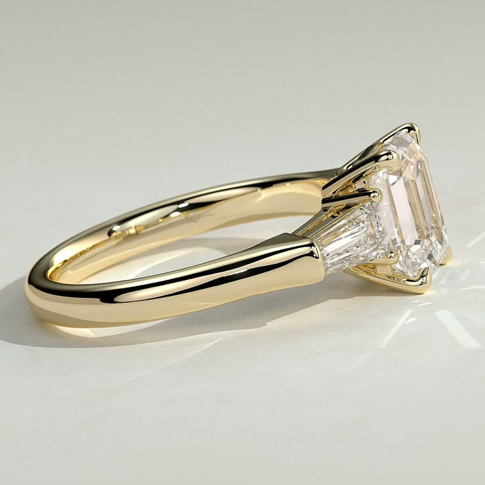 Emerald cut moissanite three stone engagement ring with tapered baguette sides in yellow gold, view 2
