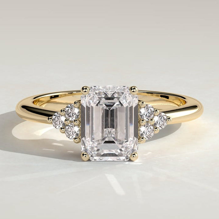 Emerald cut moissanite engagement ring with triangular cluster shoulders in yellow gold