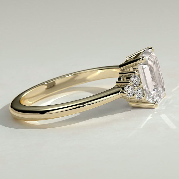 Emerald cut moissanite engagement ring with triangular cluster shoulders in yellow gold, view 2