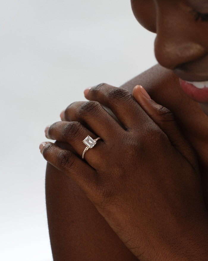 Emerald cut lab grown diamond twisted pave engagement ring worn on the hand resting on the shoulder