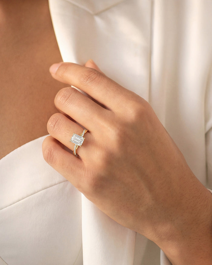 Emerald cut lab grown diamond braided band ring in yellow gold worn on the hand against a cream jacket