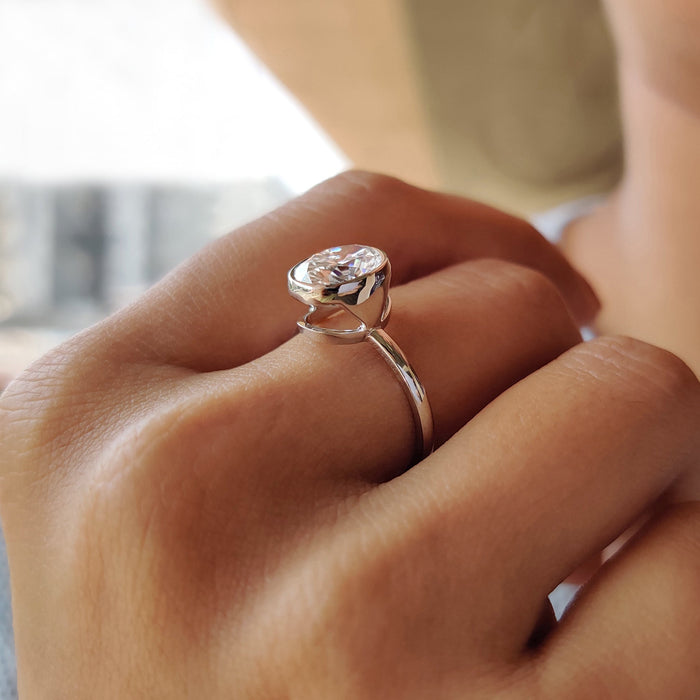 East west oval cut moissanite full bezel engagement ring on a flat white gold band, view 2