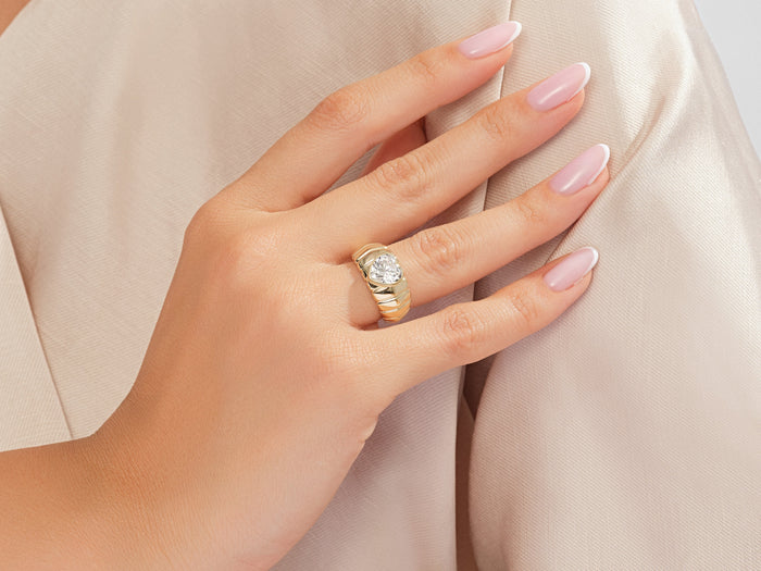 Heart lab grown diamond ribbed dome ring in yellow gold worn on the hand against beige satin