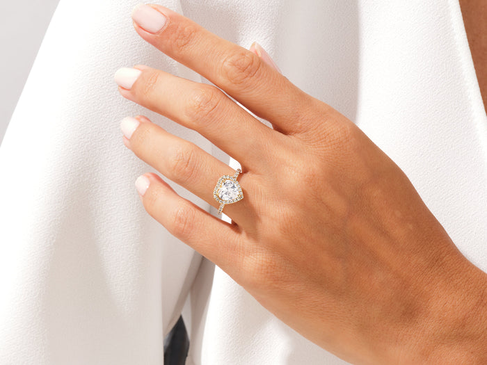 Heart cut lab grown diamond halo ring worn on an outstretched hand against white fabric