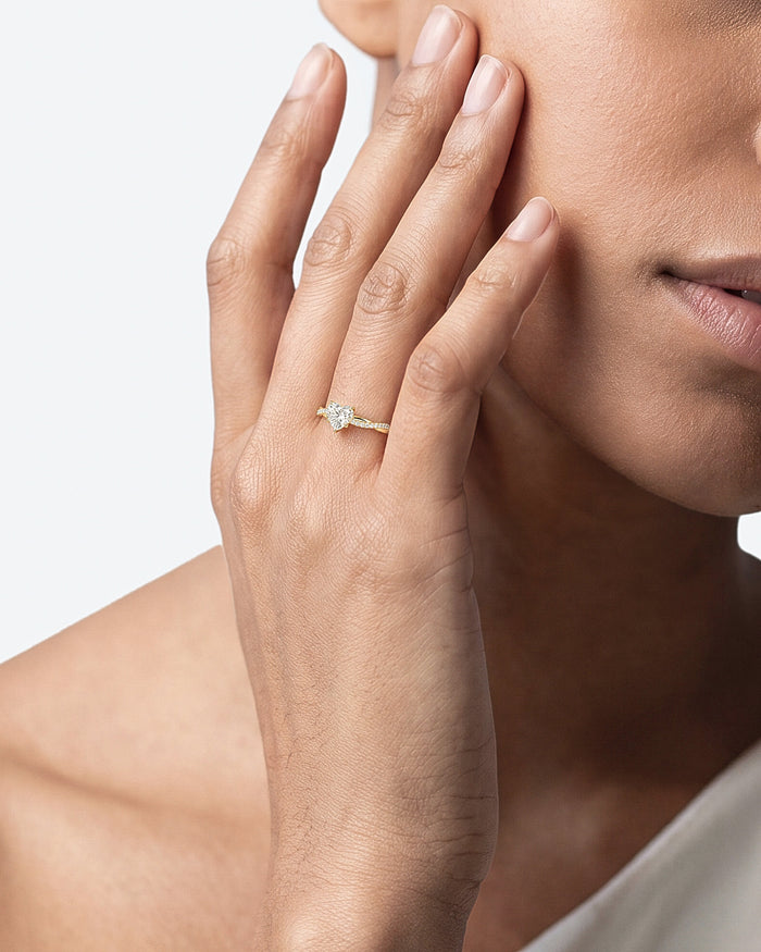 Heart moissanite twisted pave ring in yellow gold worn on the hand near the face