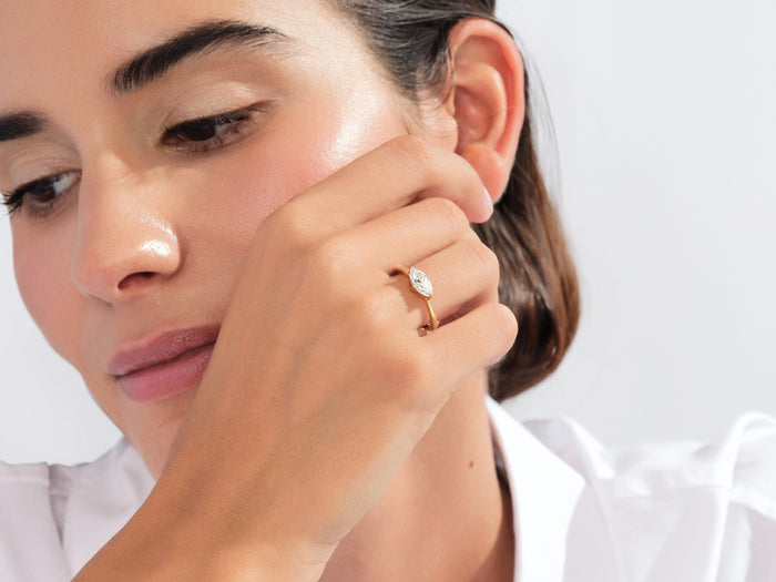 Marquise lab grown diamond east west solitaire in yellow gold worn with the hand at the cheek