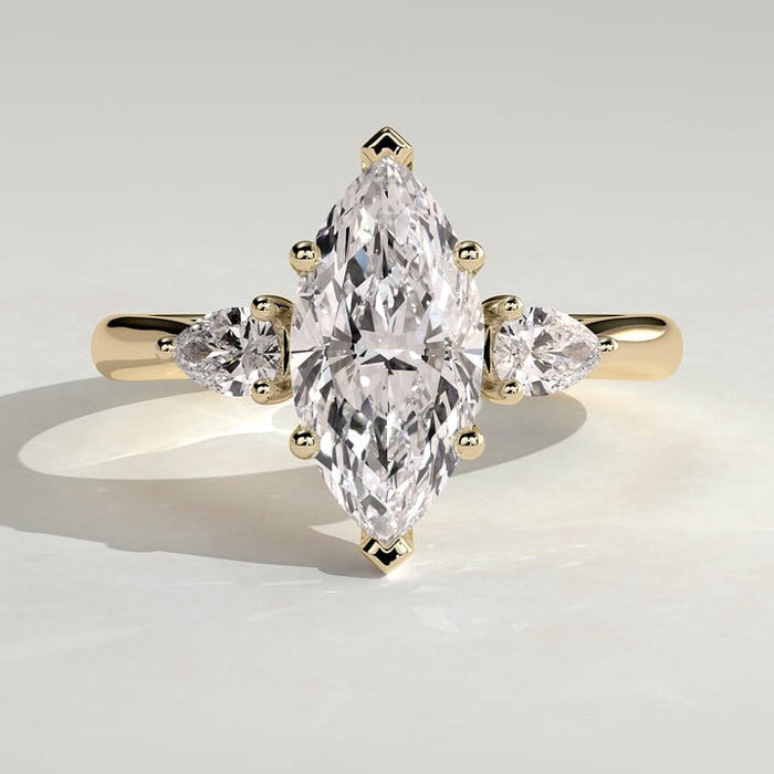 Marquise moissanite three stone engagement ring with pear side stones on a fine yellow gold band