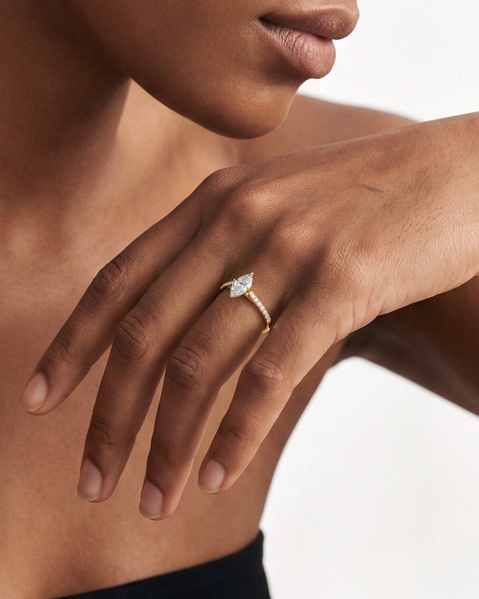 Dainty marquise lab grown diamond ring in yellow gold worn on a hand resting across the chest