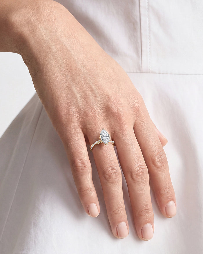 Large marquise moissanite twisted pave ring worn on the hand resting on white fabric