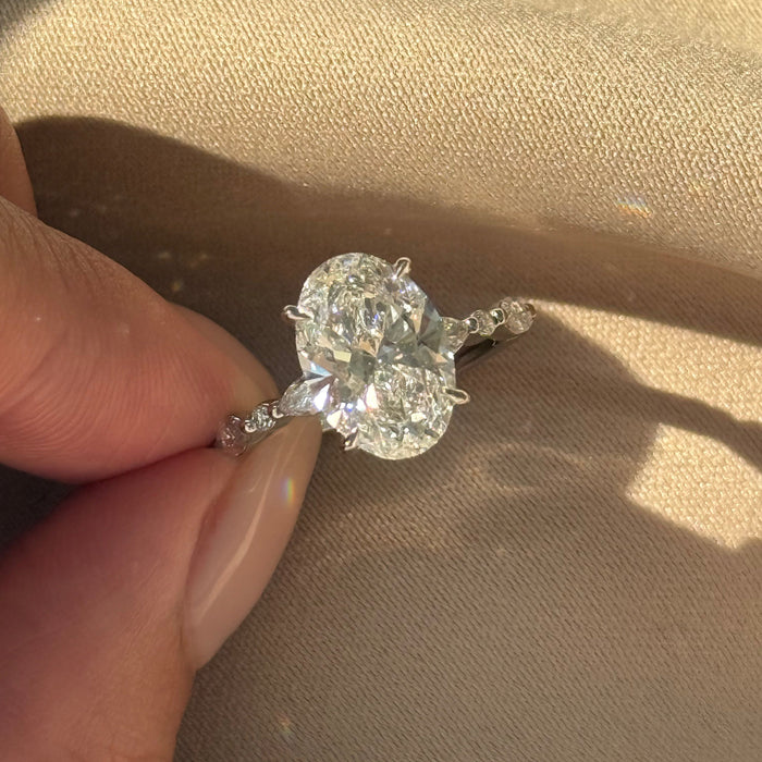 Oval cut moissanite engagement ring with marquise and round accent shoulders in white gold