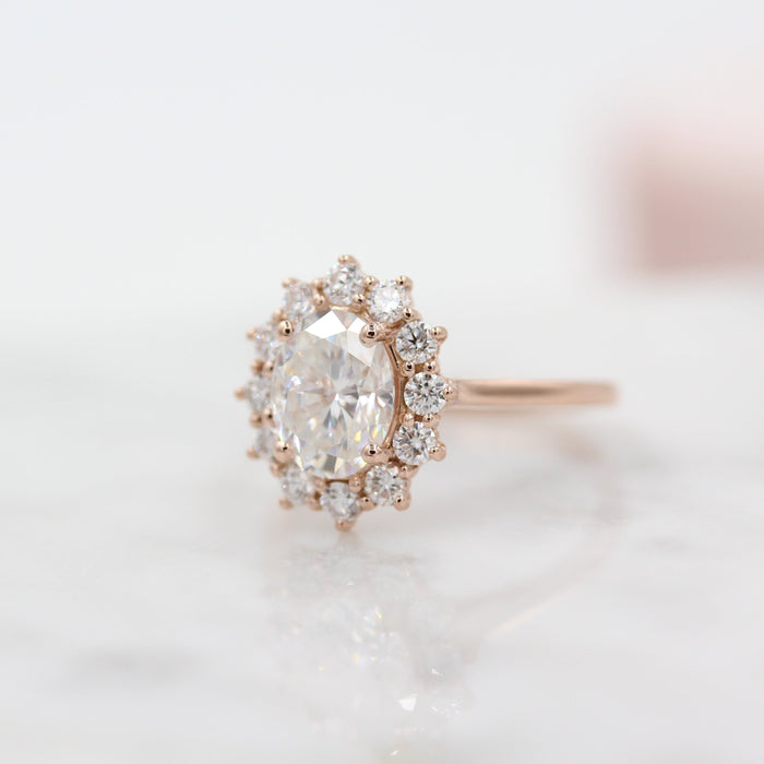 Oval cut moissanite claw set cluster halo engagement ring on a plain rose gold band, view 2