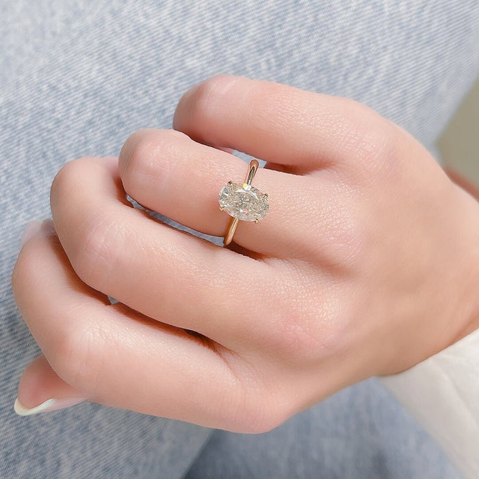Oval cut moissanite classic four claw solitaire engagement ring on a fine rose gold band