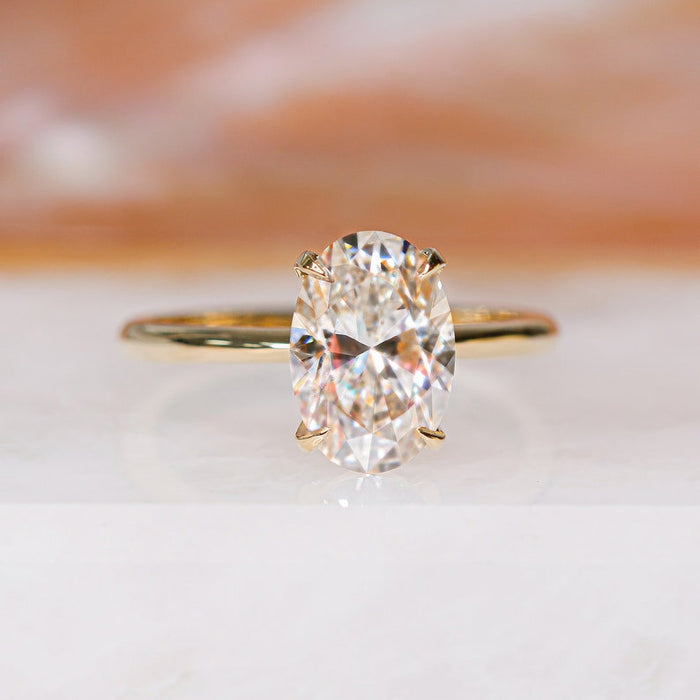 Oval cut moissanite classic four claw solitaire engagement ring on a fine rose gold band, view 2