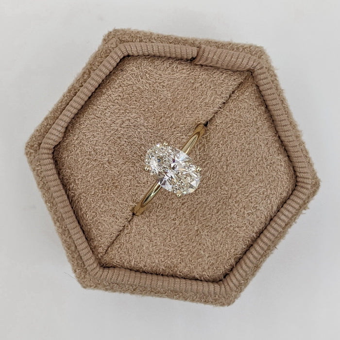 Oval cut moissanite double claw solitaire engagement ring on a fine yellow gold band