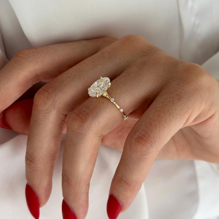 Dainty oval cut moissanite engagement ring on a thin pave band in yellow gold, view 2