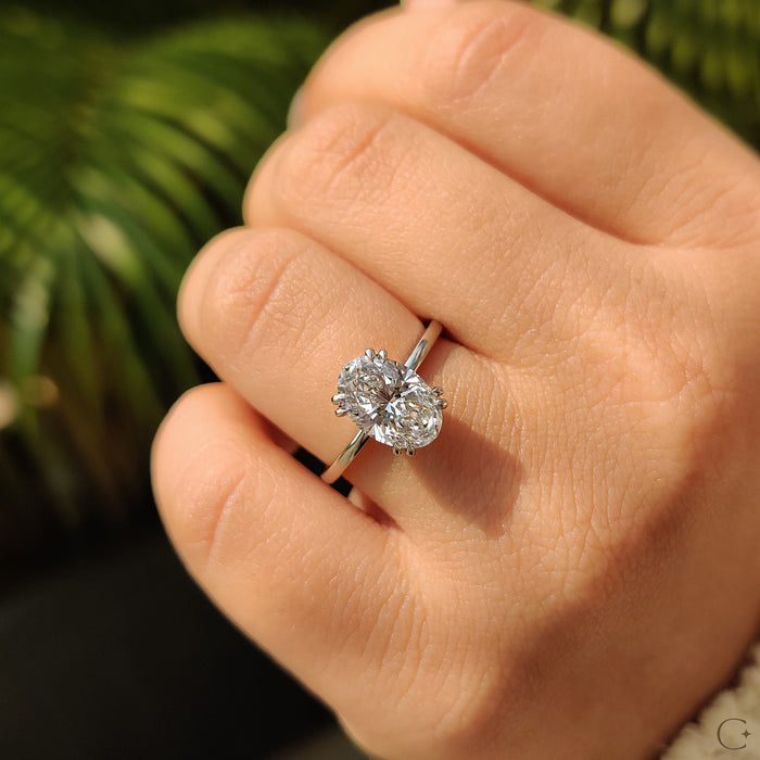 Oval cut moissanite eight claw solitaire engagement ring on a rounded white gold band, view 2