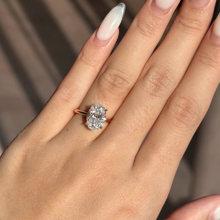 Oval cut moissanite four claw solitaire engagement ring on a fine rose gold band