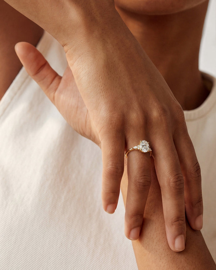 Oval lab grown diamond floral side stone ring worn on the hand resting on the forearm