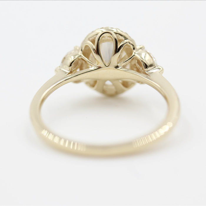 Oval cut moissanite halo engagement ring with a pair of marquises at each shoulder in yellow gold, view 2