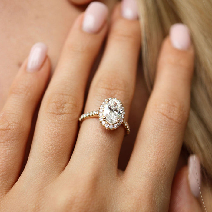 Oval cut moissanite halo engagement ring with pave band in yellow gold
