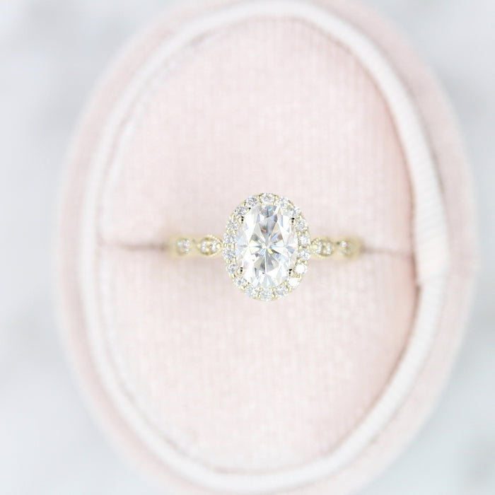 Oval cut moissanite halo engagement ring on a marquise panel band in yellow gold