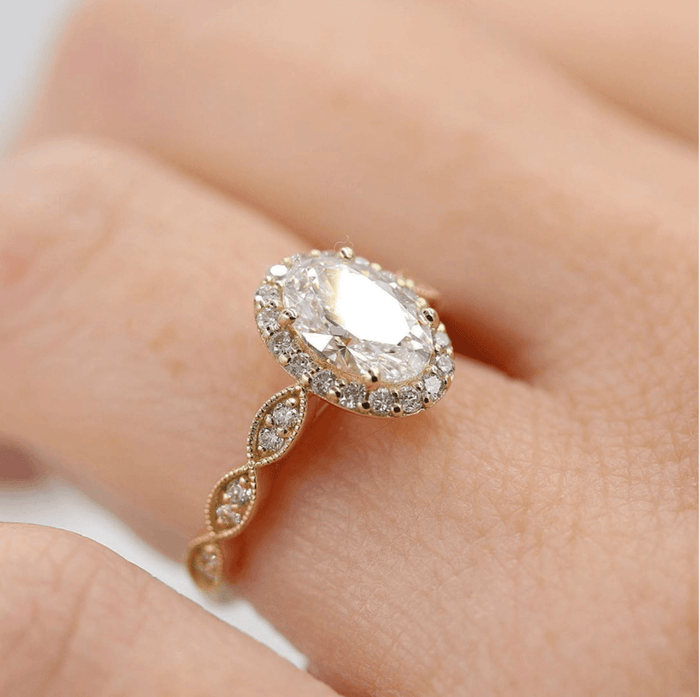 Oval cut moissanite halo engagement ring on a marquise panel band in yellow gold, view 2