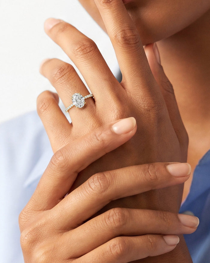 Oval moissanite hidden halo ring in yellow gold worn on the hand, close view