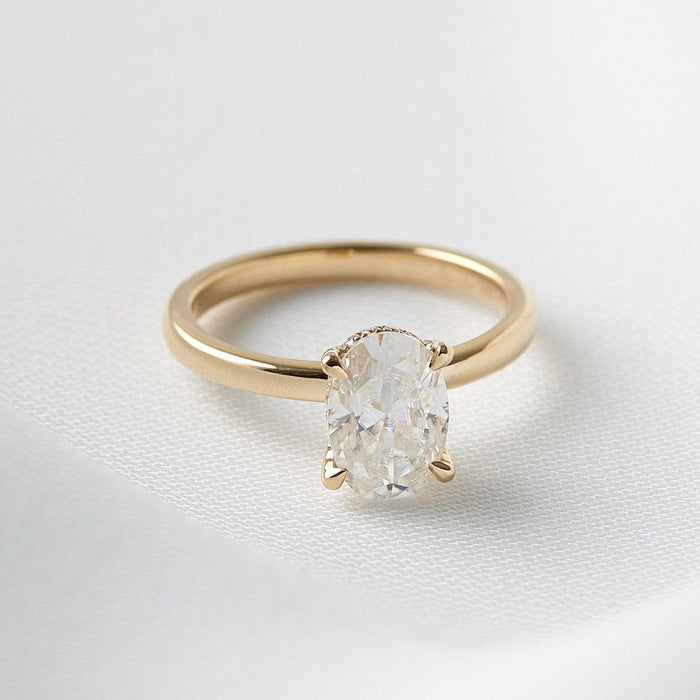 Oval cut moissanite hidden halo engagement ring on a satin finished yellow gold band