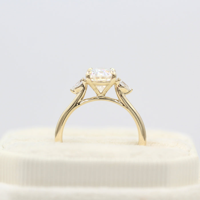 Large oval cut moissanite three stone engagement ring with pear sides on a fine yellow gold band, view 2