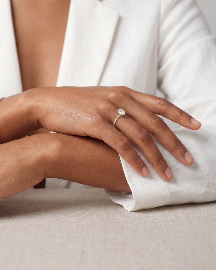 Oval lab grown diamond pave ring in yellow gold worn on the hand with a white linen sleeve