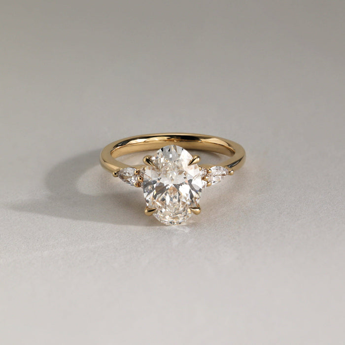 Oval cut moissanite engagement ring with pear and round cluster shoulders in yellow gold, view 2