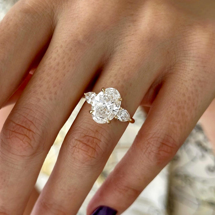 Oval cut moissanite three stone engagement ring with pear side stones in yellow gold, view 2