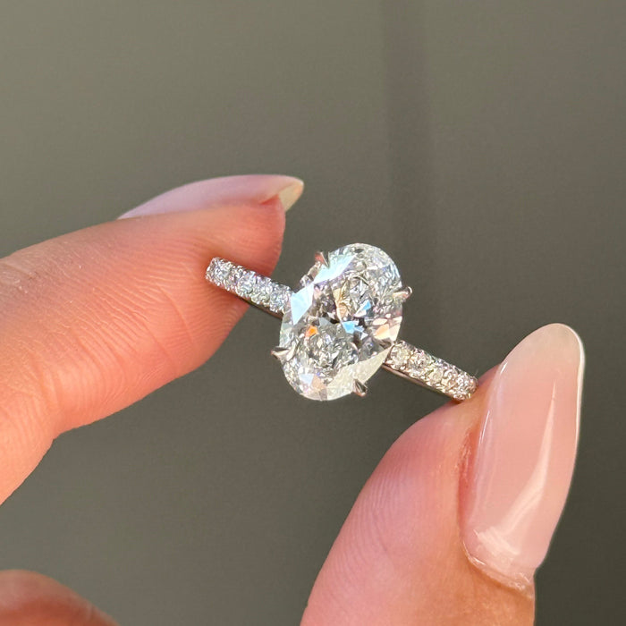 Oval cut moissanite solitaire engagement ring on a pave set white gold band