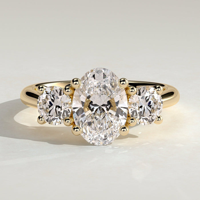 Oval cut moissanite three stone engagement ring with round side stones in yellow gold