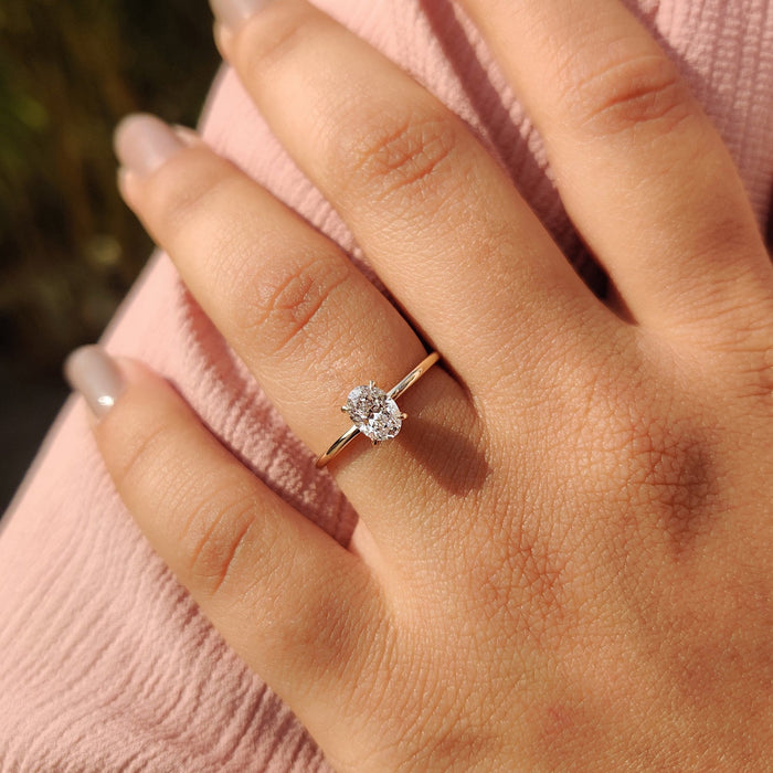 Oval cut moissanite six claw solitaire engagement ring on a flat yellow gold band, view 2
