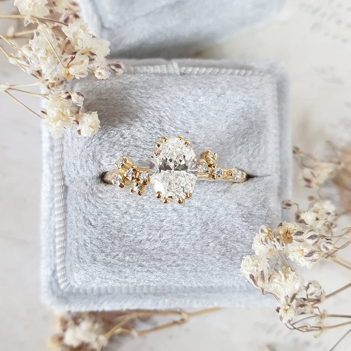Oval cut moissanite double claw engagement ring with scattered cluster shoulders in yellow gold