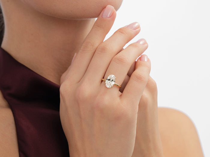 Elongated oval lab grown diamond solitaire worn on the hand raised to the chin