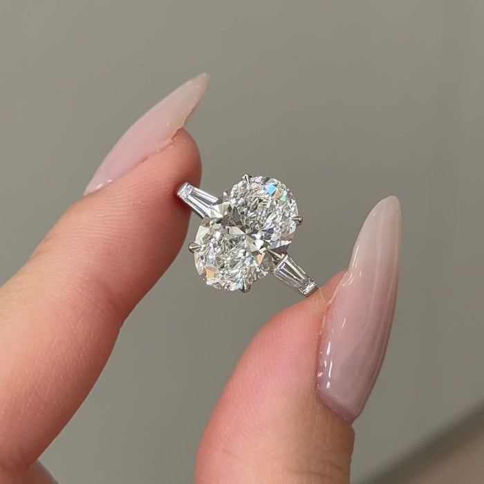 Oval cut moissanite three stone engagement ring with tapered baguette sides in white gold