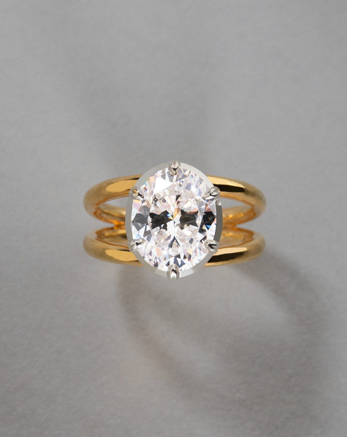 Oval cut moissanite in a white head on a two tone double shank in yellow gold