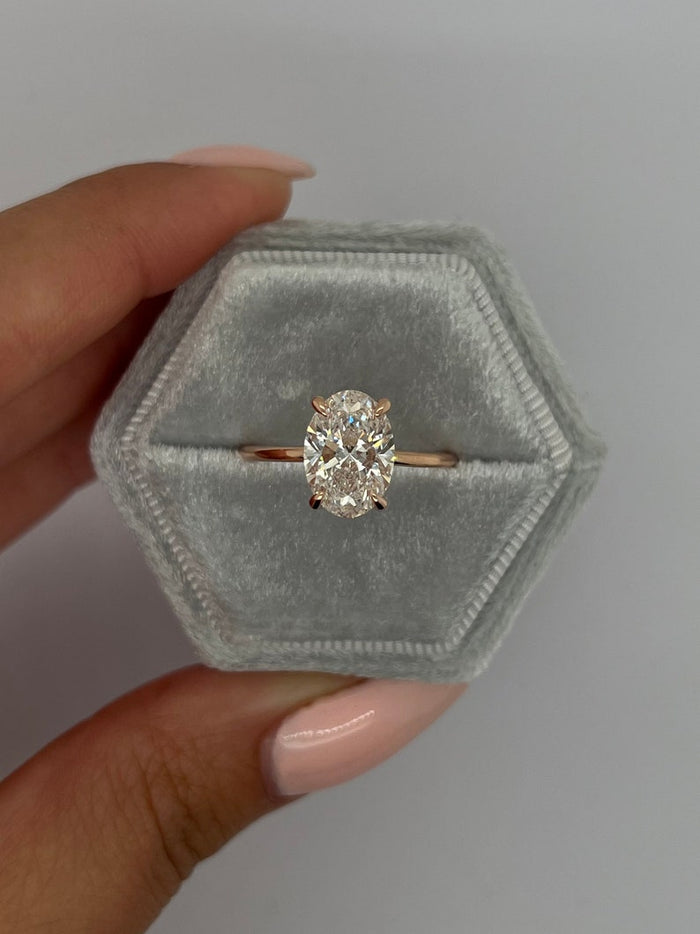 Oval cut moissanite solitaire engagement ring on a tapered knife edge rose gold band