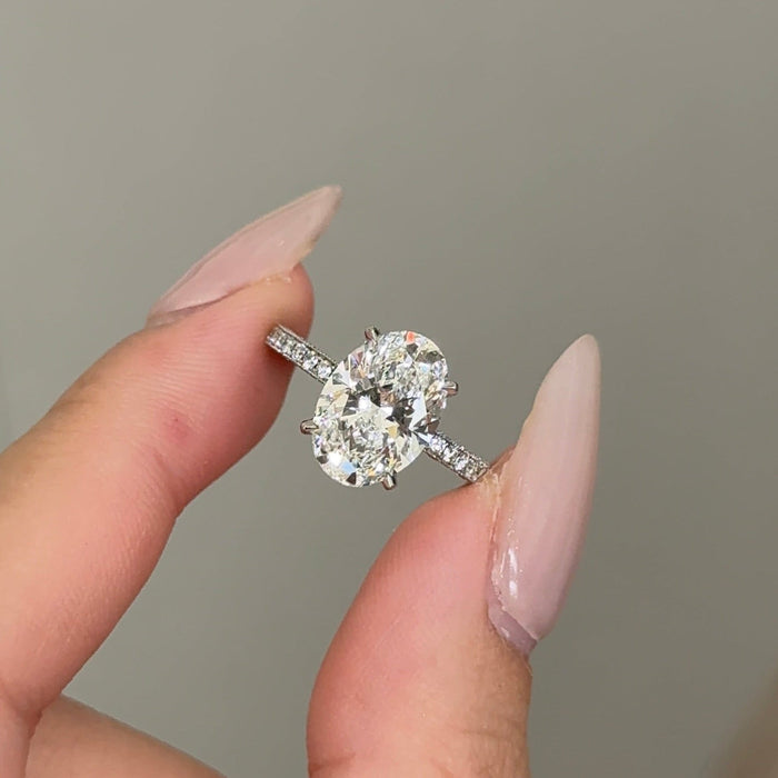 Oval cut moissanite hidden halo engagement ring with three sided pave shank in white gold