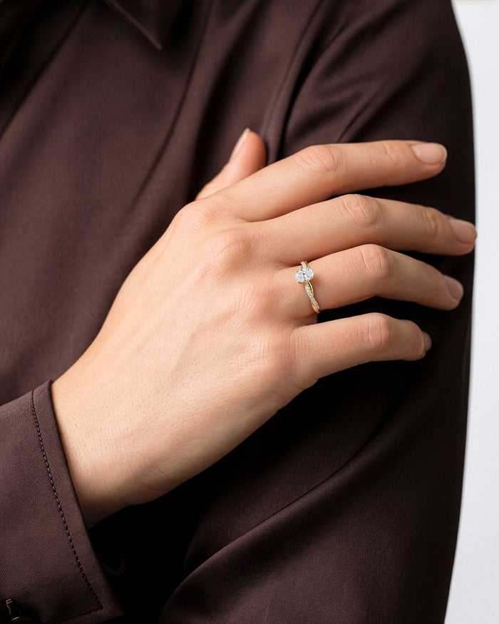Oval lab grown diamond twist ring worn on the hand resting on the shoulder of a brown shirt