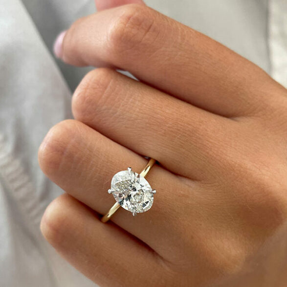 Oval cut moissanite solitaire engagement ring on a tapered plain yellow gold band, view 2