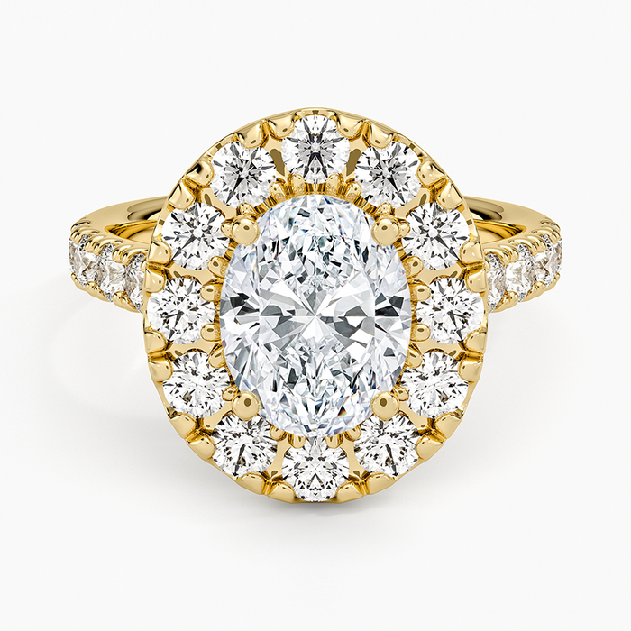 Oval moissanite with a bold round halo and pave shoulders in yellow gold, top view