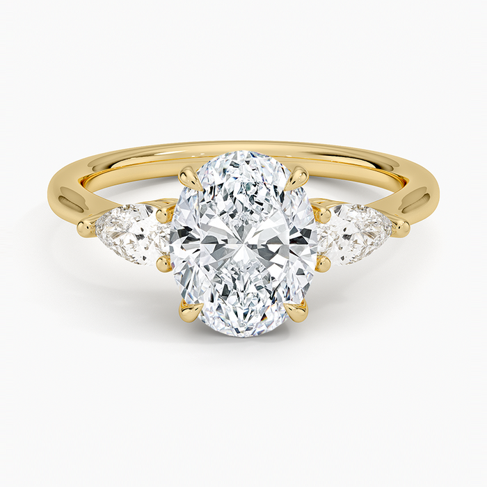 Oval moissanite three stone ring with large pear side stones in yellow gold, top view