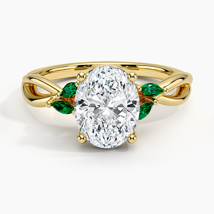 Oval moissanite ring with green marquise emerald leaves on a twisted yellow gold vine, top view