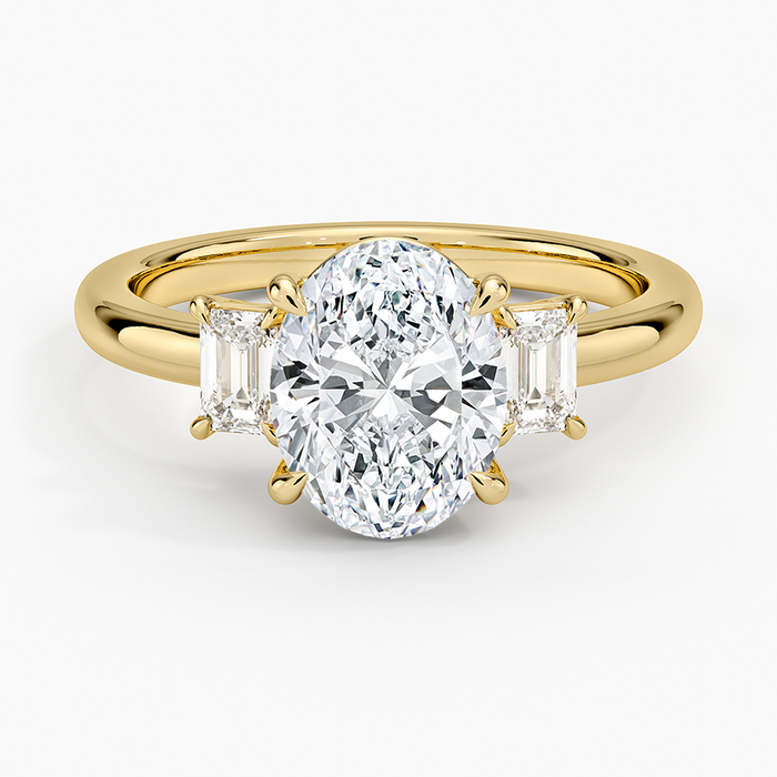 Oval moissanite with emerald cut side stones in yellow gold, top view